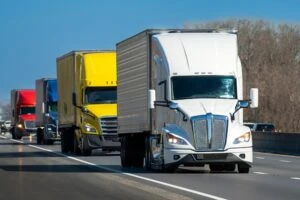 A convoy of 18-wheelers driving down the highway. A lawyer can explain how liability is determined in 18-wheeler accidents.