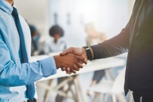 A lawyer and client shaking hands after discussing how to negotiate a higher truck accident settlement.