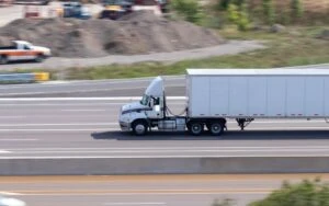 A white semi truck speeds down a highway, leading other drivers to wonder what to do after an 18-wheeler accident.