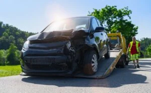 A tow truck driver towing a car after an accident.