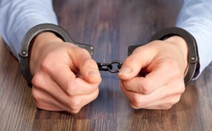 a close-up of a man’s hands in handcuffs