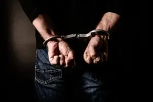 man in jeans with hands in handcuffs