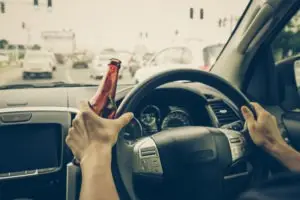 a driver holding an open beer bottle while driving