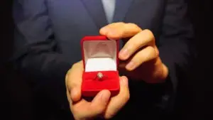 a well dressed man presents an engagement ring