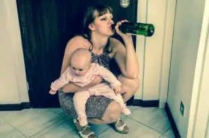 a woman holding a baby and drinking alcohol