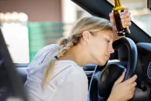 a young female driver holding a beer bottle