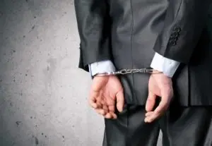 businessman wearing suit in handcuffs