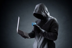 hacker using stolen credit card with laptop