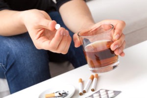 man putting pill in alcohol