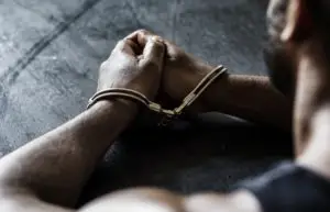 man sits with hands cuffed in front of him