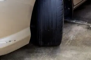 Photo showing the bald front-right tire of a beige-colored car