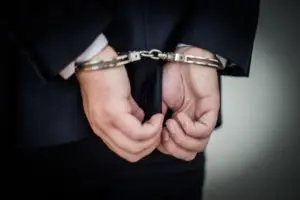 businessman wears handcuffs behind back