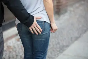man touching woman’s buttocks