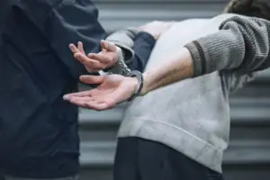 officer holds onto handcuffed suspect by arm