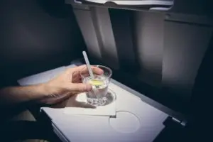 A passenger holds a cocktail on their tray table.