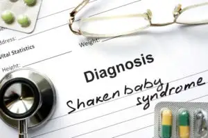 diagnosis shaken baby syndrome written on a doctor’s form with glasses pills and a stethoscope