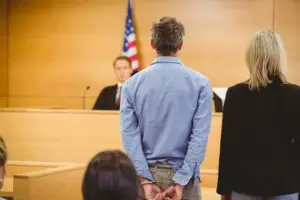 a man in handcuffs and his lawyer standing before a judge