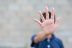 a young child holding their hand out in a plea to stop