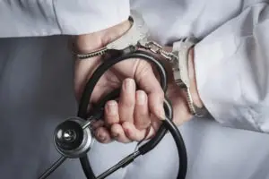 doctor in handcuffs holding stethoscope