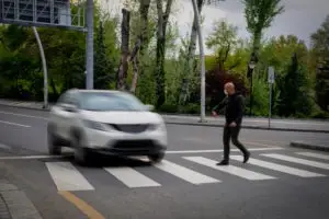 car speeding through crosswalk with pedestrian