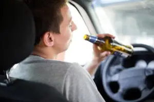man drinking beer in car