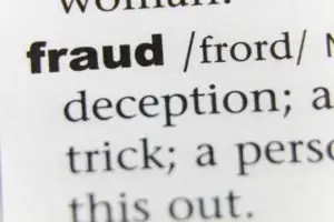 a closeup of the word fraud in a dictionary
