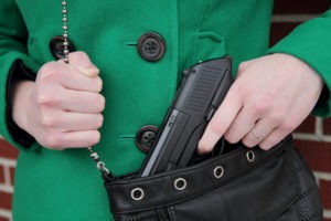 a woman pulling a gun from her purse