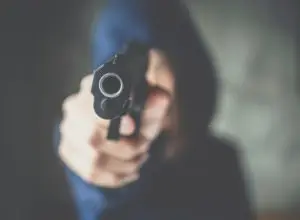 hooded figure pointing gun