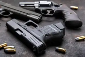 three handguns surrounded by ammunition