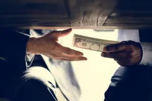 a man handing cash to another under the table
