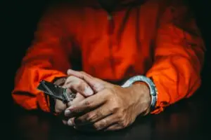 an inmate in handcuffs holding a knife