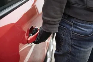 a gloved car thief checking a door handle