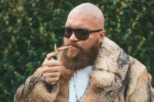 bald man wearing glasses and smoking marijuana in fur coat