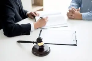 gavel in front of two men at table working on legal forms