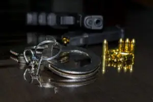 handgun and magazine in background with bullets and handcuffs in foreground