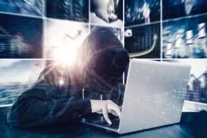 masked hacker uses laptop