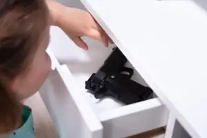 small child reaching into drawer for gun