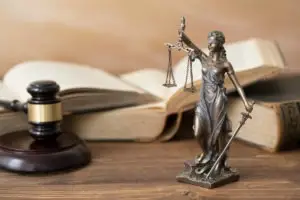 statue of justice and gavel in front of law books