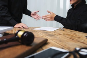 two men about to shake hands behind desk with gavel