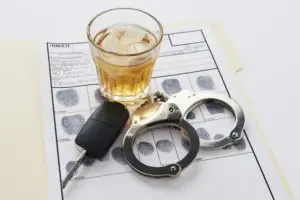 car keys glass of whiskey and handcuffs on fingerprint sheet