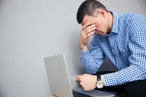 depressed man holding credit card over laptop