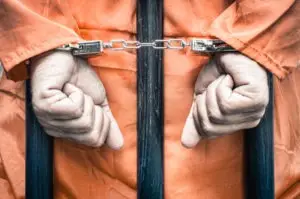 handcuffed prisoner hands behind bars