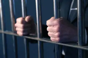 man behind bars gripping bars