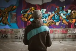 man-standing-near-a-wall-of-graffiti
