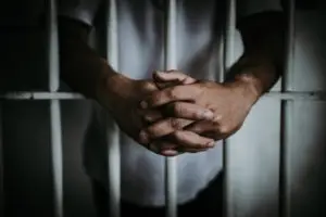 prisoner clasping hands behind cell