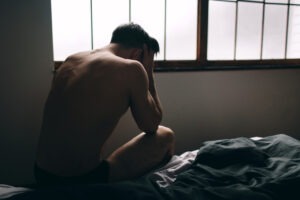 distressed man sitting on bed