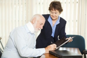 A man with a neck brace signing forms for a female L.A. personal injury attorney.