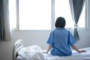 sad female patient sitting on a bed