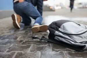 man with backpack falling on slippery sidewalk