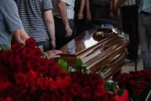 people placing roses on top of a casket
